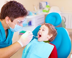 Young boy smiling while pediatric dentist examines his teeth