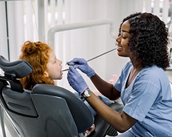 Dental hygienist smiling while cleaning child's teeth