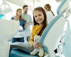 Child smiling while dentist and parents discuss nitrous oxide