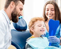 Child smiling at reflection in tooth-shaped mirror