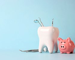A piggy bank and tooth model set against a blue background