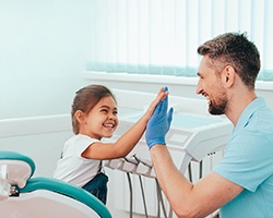A young girl high-fiving her pediatric dentist